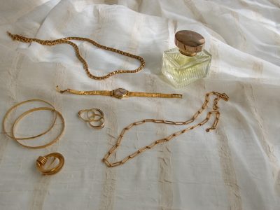 Woman accessories – golden jewelry on beige textile Woman accessories - golden jewelry on beige textile